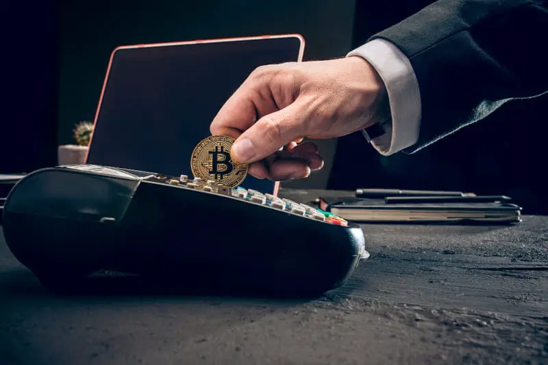A man trying to swipe a bitcoin like he would a credit card. Bitcoin does not store value like gold, so its value is assumed.