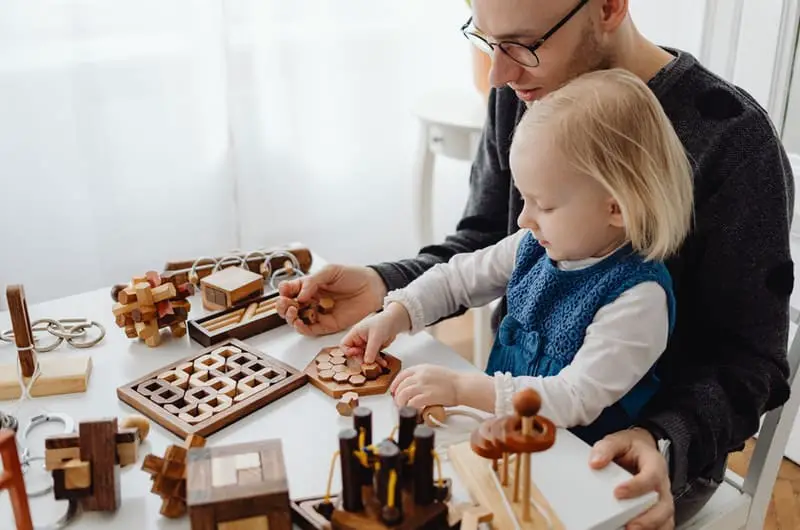 A young dad is playing with his toddler girl. His "why" to becoming a millionaire is to be financially independent for the safety and comfort of his family.