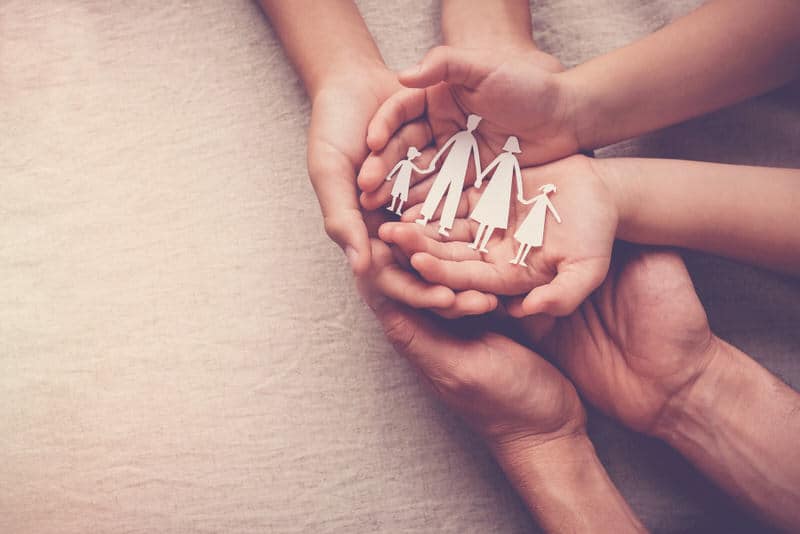 A family bringing out their hands together to show "embrace".