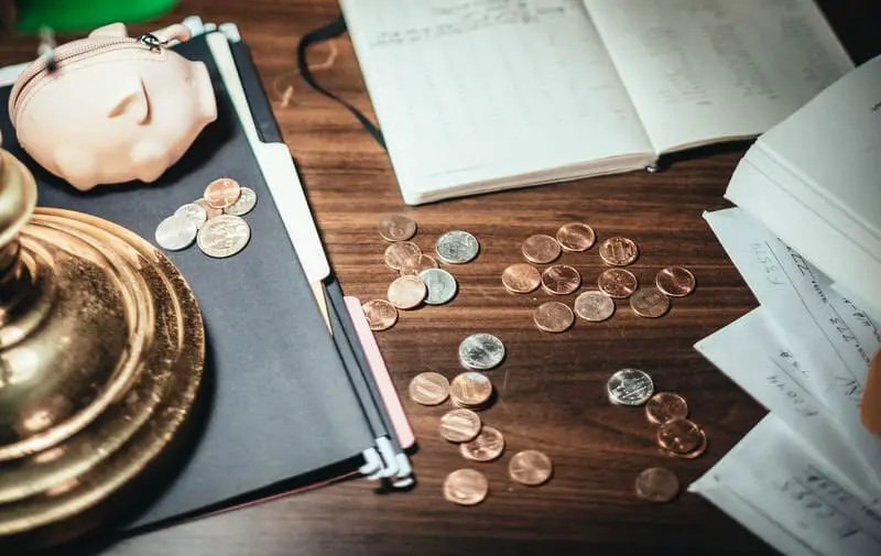 Pennies and other coins are laid out on a work desk.