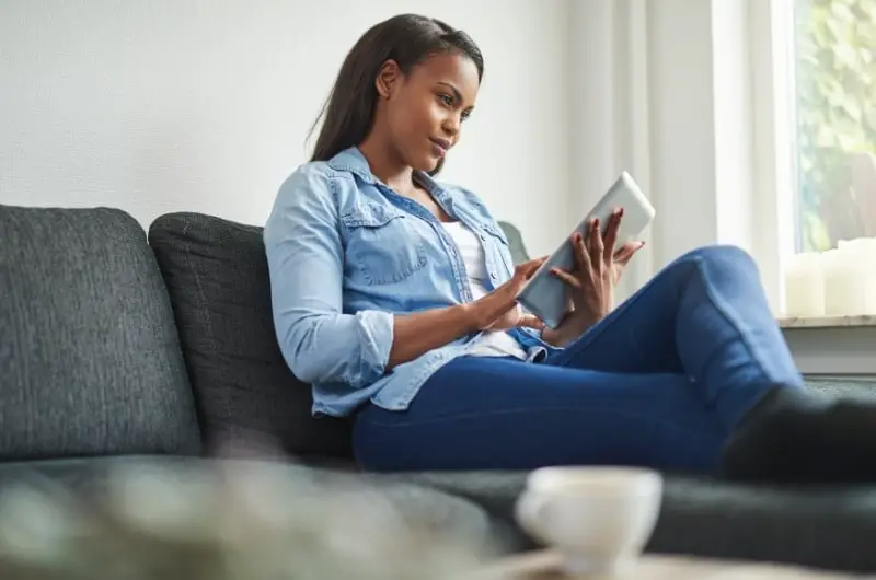 A young woman is sitting on her sofa, planning her budgeting to accommodate her living-alone lifestyle.