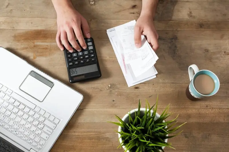 A young individual is sitting at his work desk, ready to prepay his mortgage with some extra money he has in his bank account.