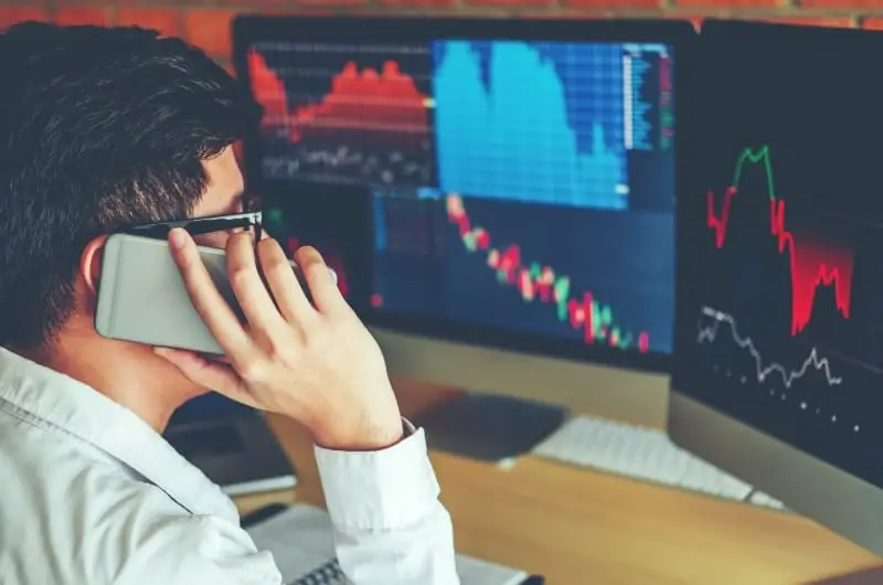 A young investor is on the phone, stressing out after seeing what looks like a stock market correction on his live trading app.