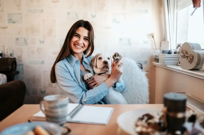 A young woman is happy after moving into a more affordable apartment with her dog.