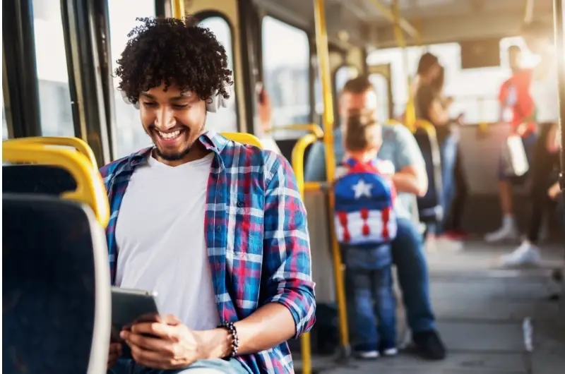 A young man is using public transportation to save money on car expenses.