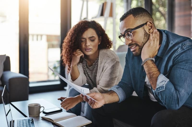 A young couple is looking over their recent spending habits together.