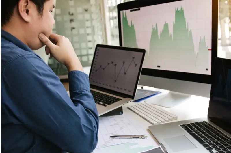 A young man is looking over his investments on his computer.