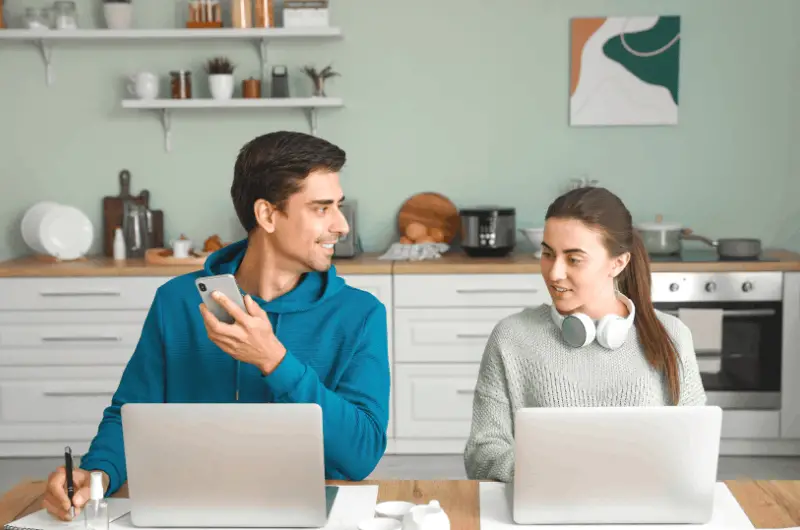 A young couple is sitting at the dining table, figuring out where to live together in the US on a $5,000 a month combined salary.