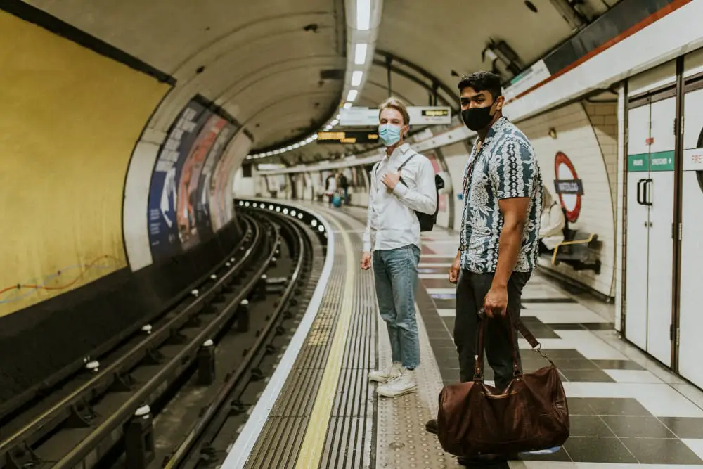 Two young guys are waiting for the train to come, they're commuting to work to save money