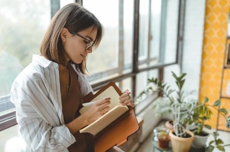 A woman who works from home is taking some time in the morning to journal for self development