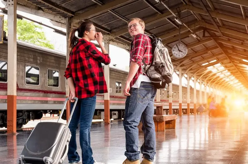 A young couple is getting around in Europe on a train as their primary mode of affordable transportation to various cities.