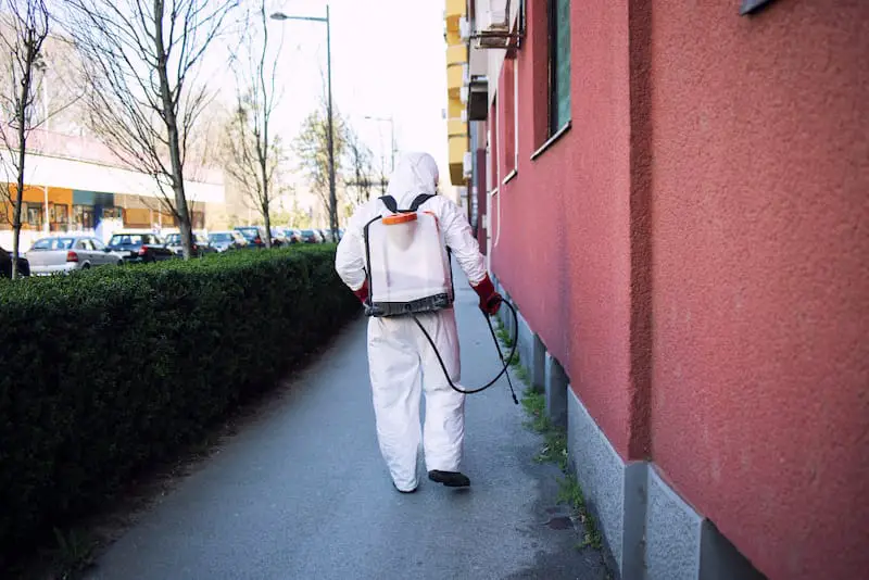 A pest control employee is spraying a termite bond around a customers house