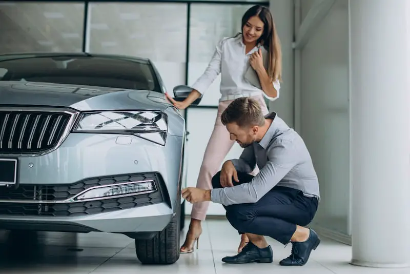 A young couple is looking at a used car to consider buying