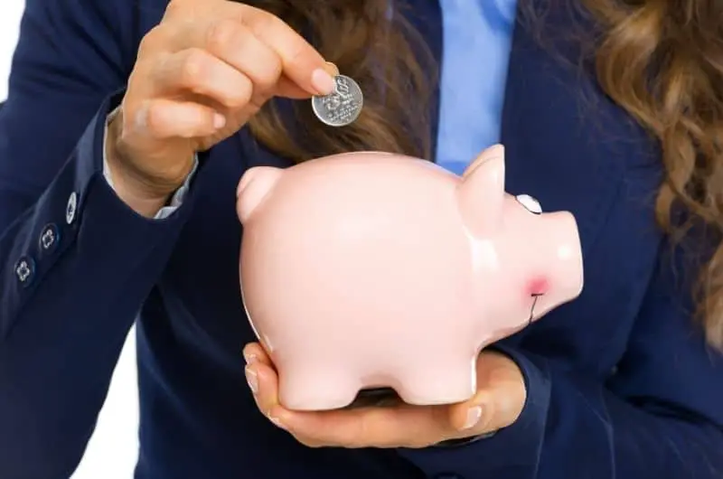 A young woman is putting a quarter inside a piggy bank.