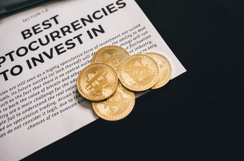 5 different gold bitcoin coins laid out on a table.
