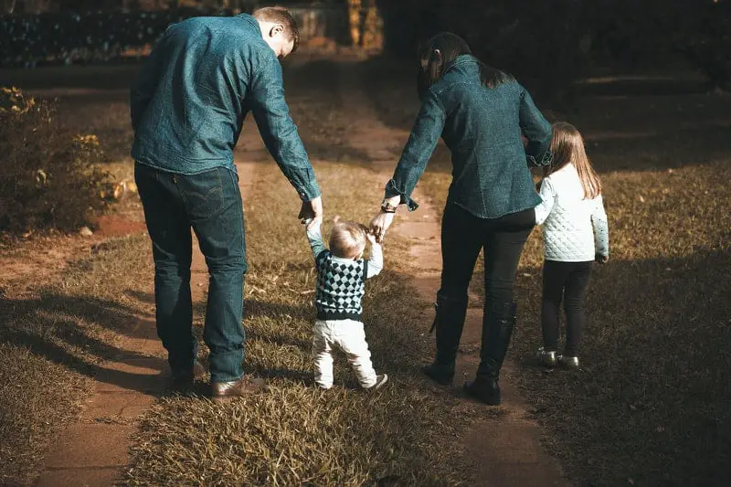 A young family of 4 are spending quality time outside by taking a walk.