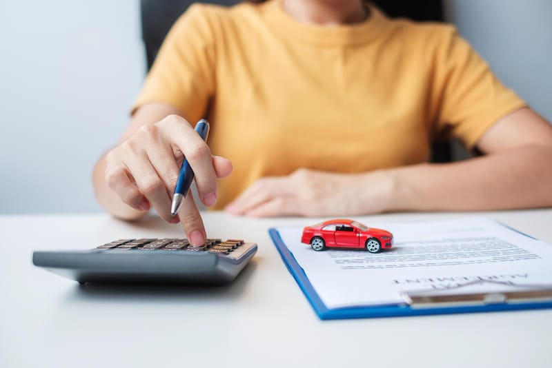 A woman is considering trading her car in and is doing the math work at home to figure things out before going to the dealership.
