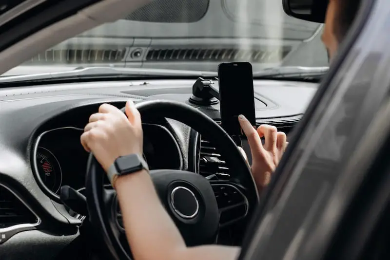 A woman wearing an Apple Watch in her car is syncing her iPhone with her watch.